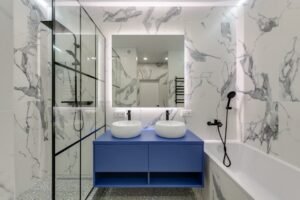 Modern bathroom interior featuring marble walls, dual sinks, and a glass shower.