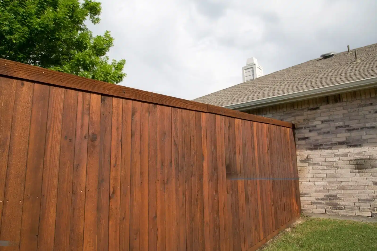 Wooden privacy fence installation beside brick home backyard in Dallas, TX