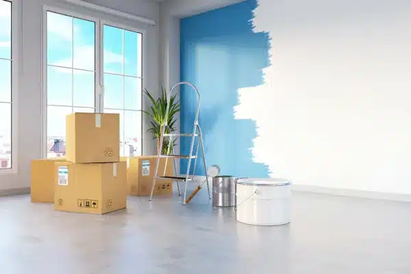 Room being painted with blue color, supplies and ladder ready for use.